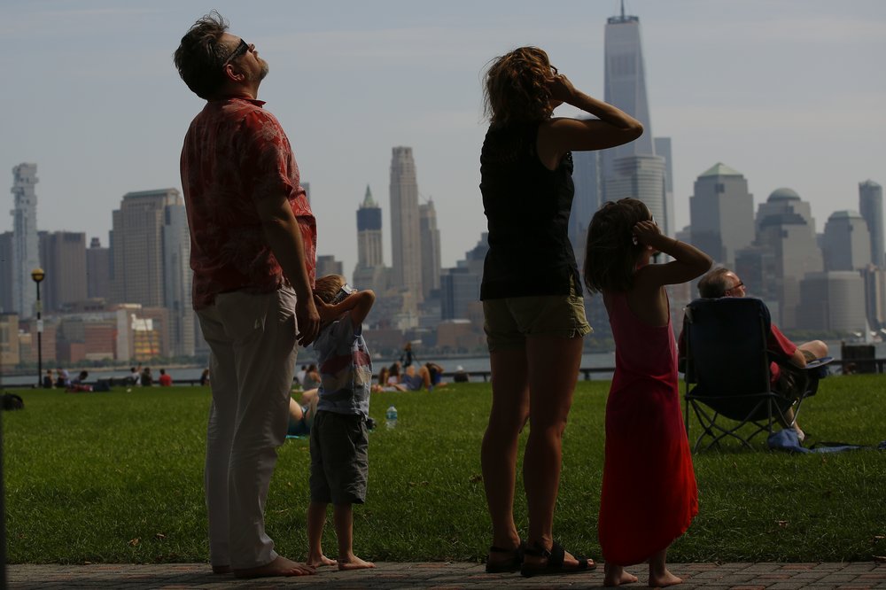 People watch the 2017 solar eclipse with glasses over their eyes in New Jersey.