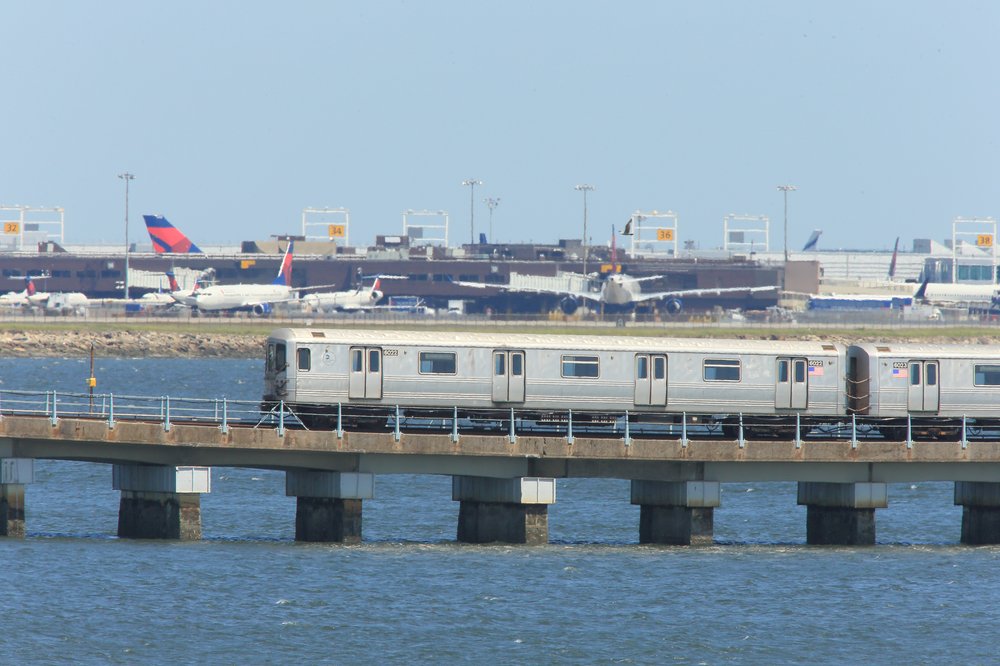 An elevated subway passes by the planes at JFK airport.
