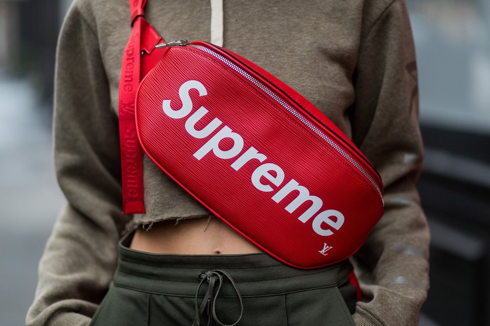 A red Supreme cross body bag that says "Supreme."