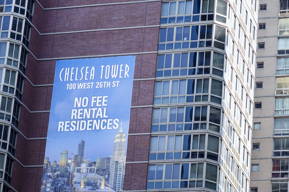 A promotion draped on the side of a building offers "no fee" apartments.