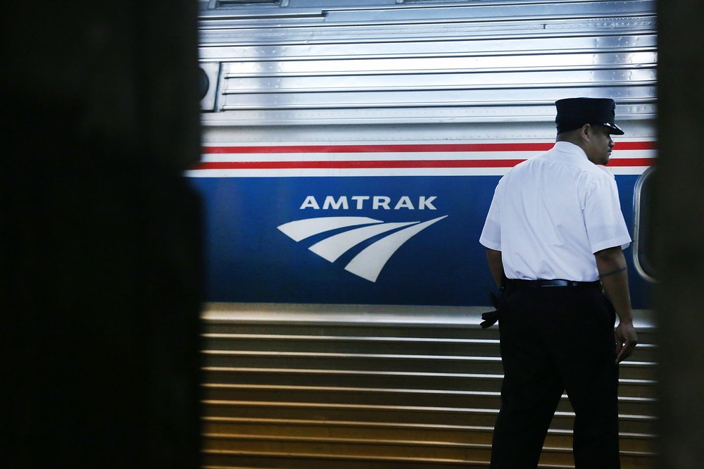 A train conductor stands next to an Amtrak train at New York's Pennsylvania Station in February 2018.