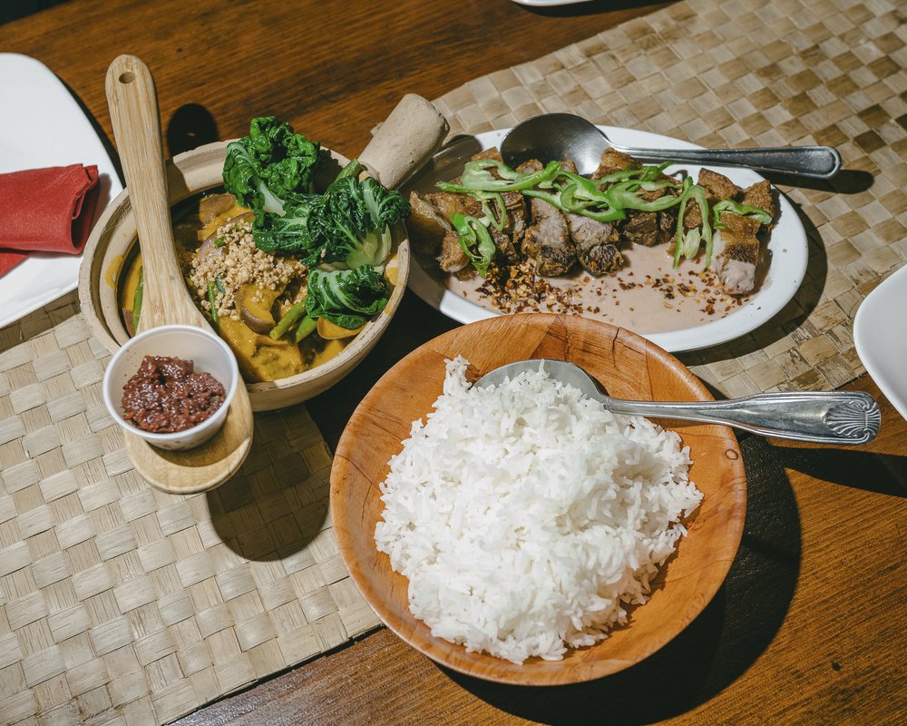 A table of food, featuring: a bowl of white rice; a bowl of soup; and a plate of small of chunks of meat.