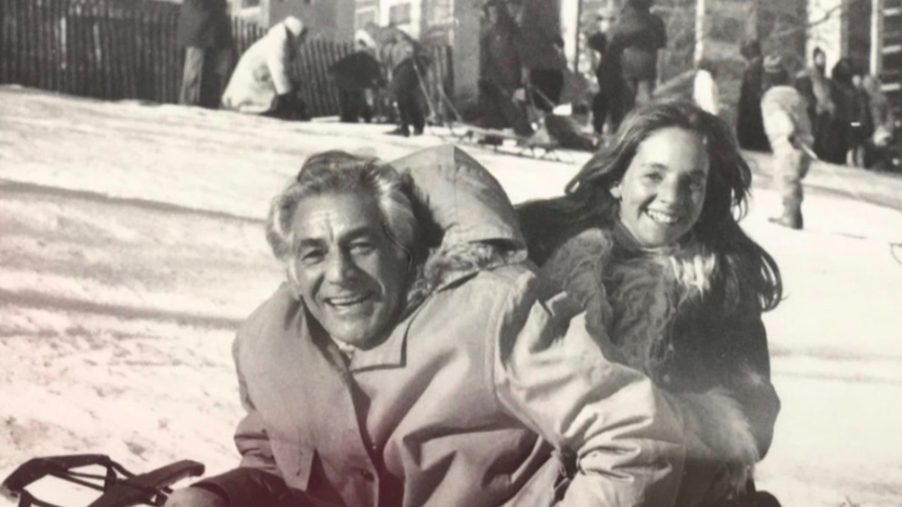 A young girl on a sled with her father in a black and white photo