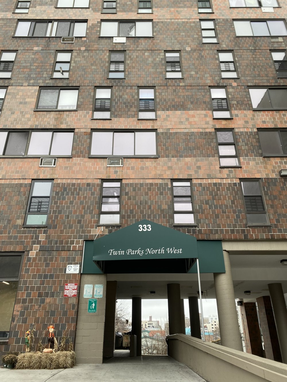 Twin Parks Northwest is a tall brick building with a green awning displaying the building name.