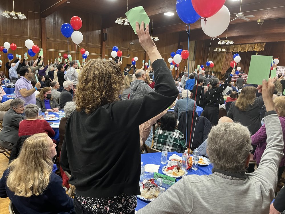 Several people in a crowded room hold up green cards.