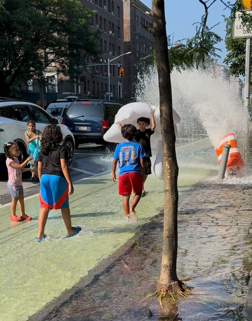 Alex Rolon sets up the impromptu lazy river by placing a traffic cone over an open fire hydrant.