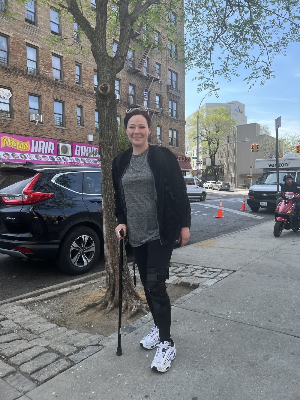 Christina Acevedo stands outside of the PATH intake center in the South Bronx, leaning on a cane.