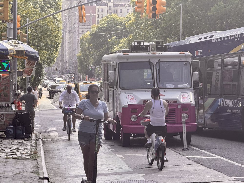 An ice cream truck parked by a busy bike lane.