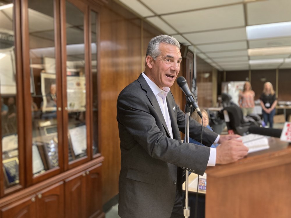 Ralph Ciattarelli stands at a lectern with wood paneling behind him