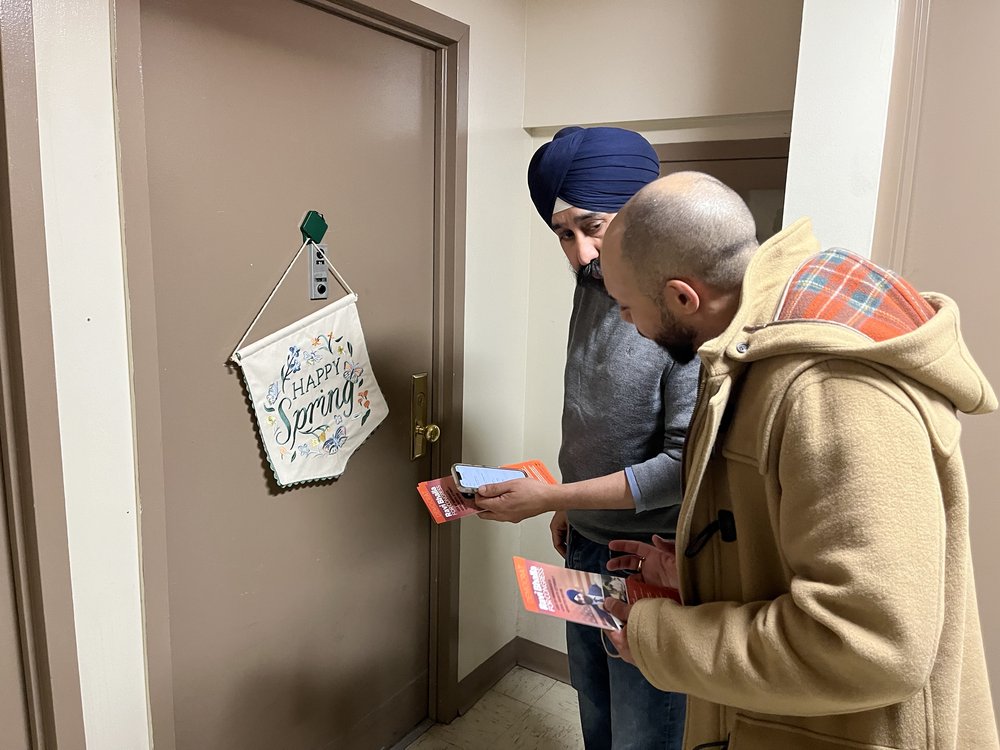 Two men knock on an apartment door.