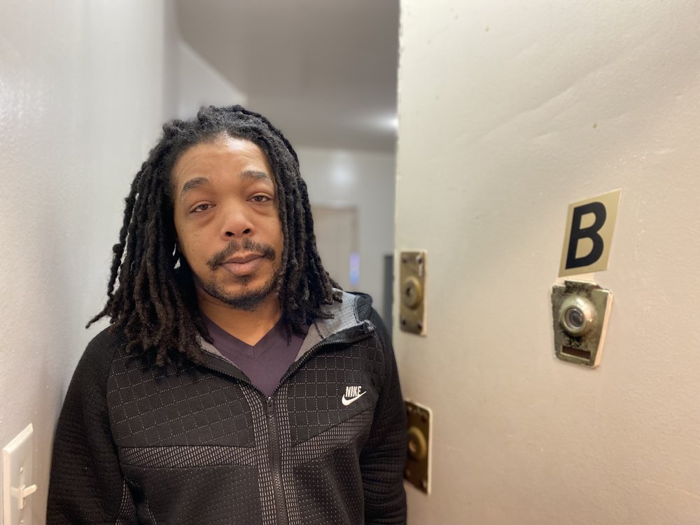 James Eley, 41, answers the door to his apartment on the Lower East Side in a black zip up sweatshirt and has shoulder-length dreadlocks