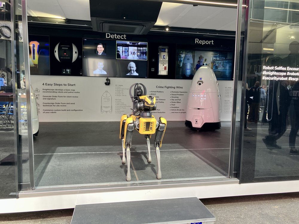 A robotic dog and a cone-like robot on display in Times Square.