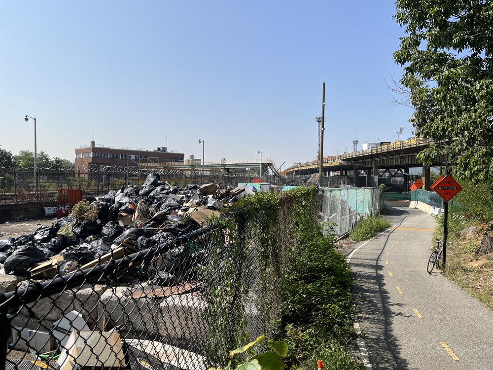 A giant pile of garbage next to a bike path.