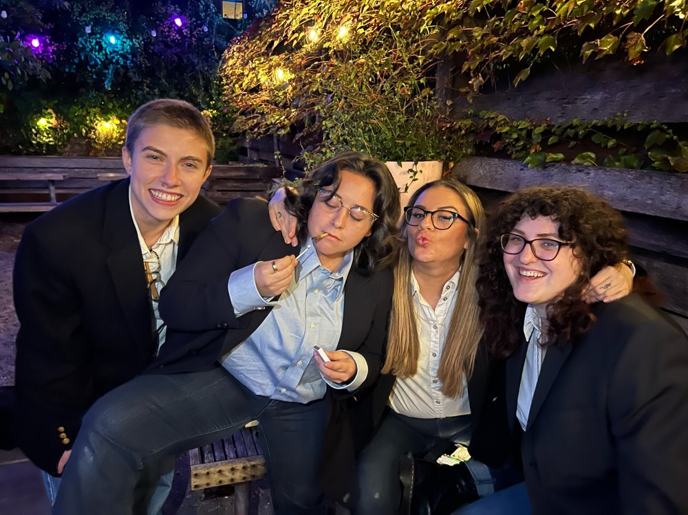 A group of people wearing dressed alike: in jeans and a blazer.