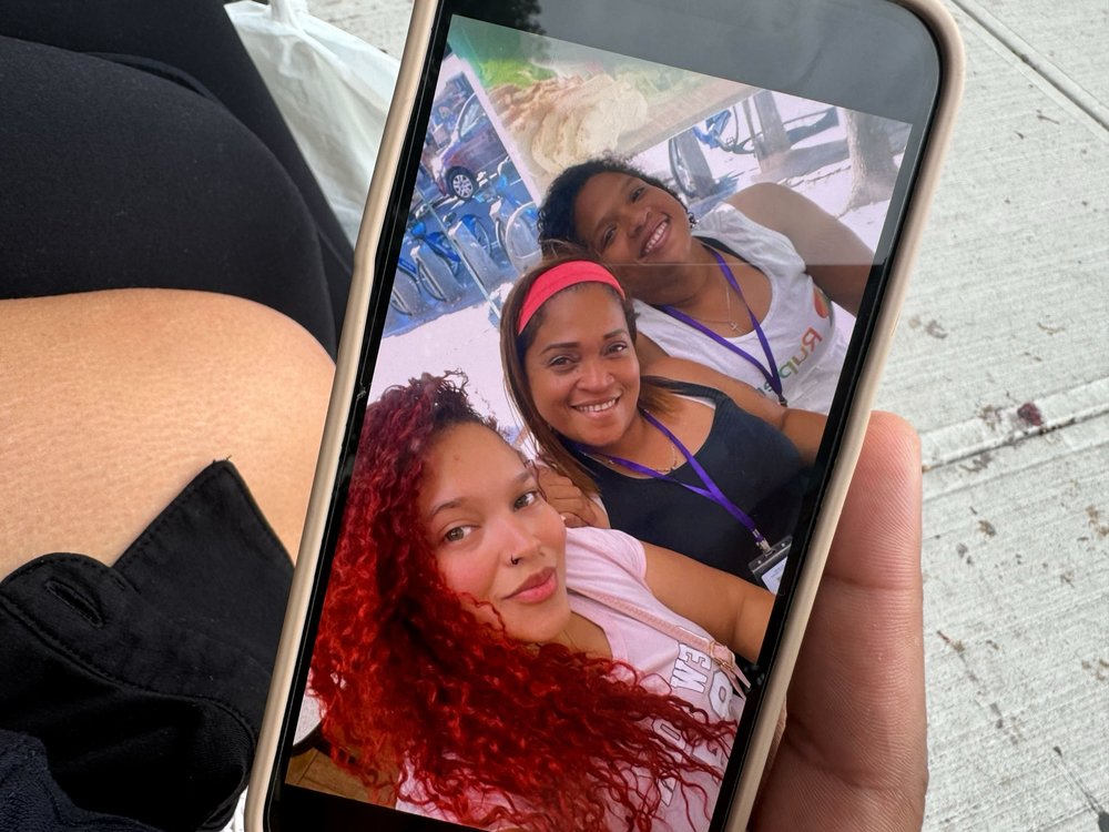 Three woman are seen in a photo on a cell phone
