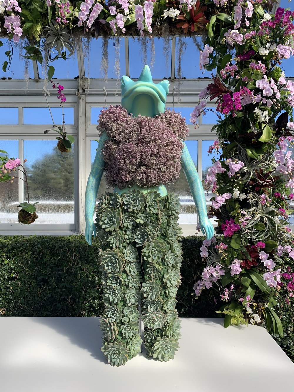 A floral statue that's a cross between a frog, an alien and a rhino.