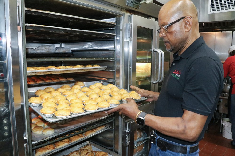 A man inspects items on a baking tray before they go into the oven.