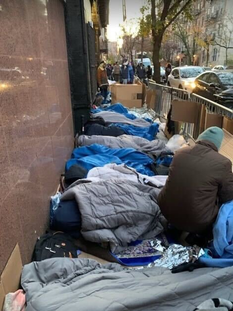Migrants waiting for new shelter placements rest outside the St. Brigid reticketing site in the East Village around 7 a.m. Wednesday.