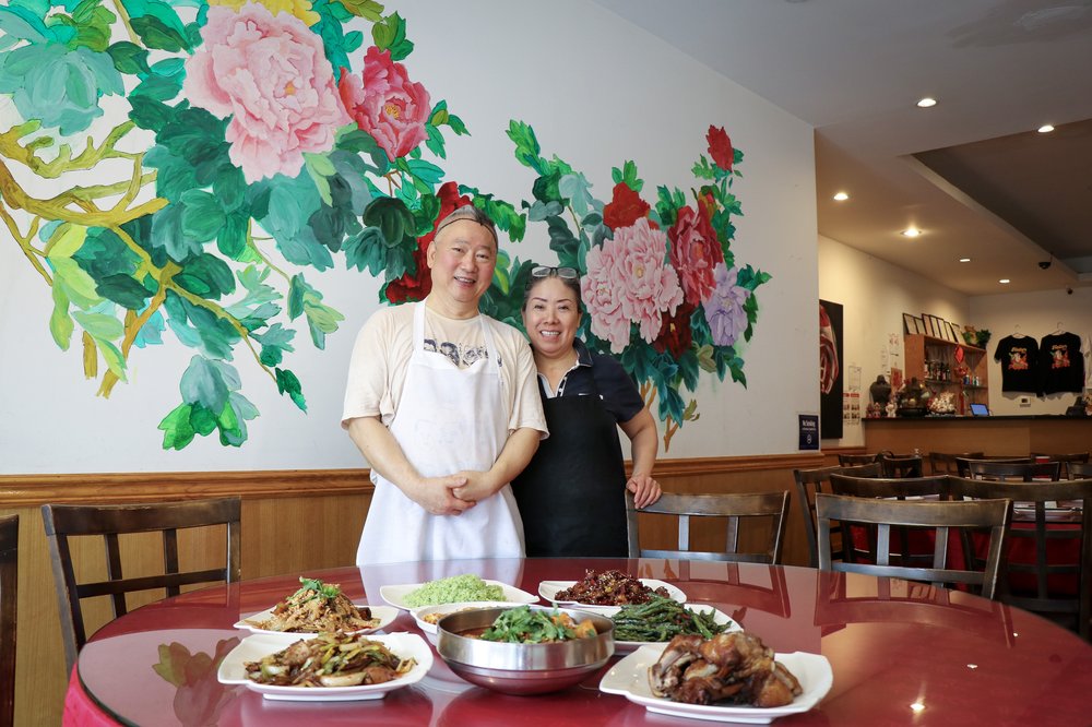 A couple poses in front of a red table