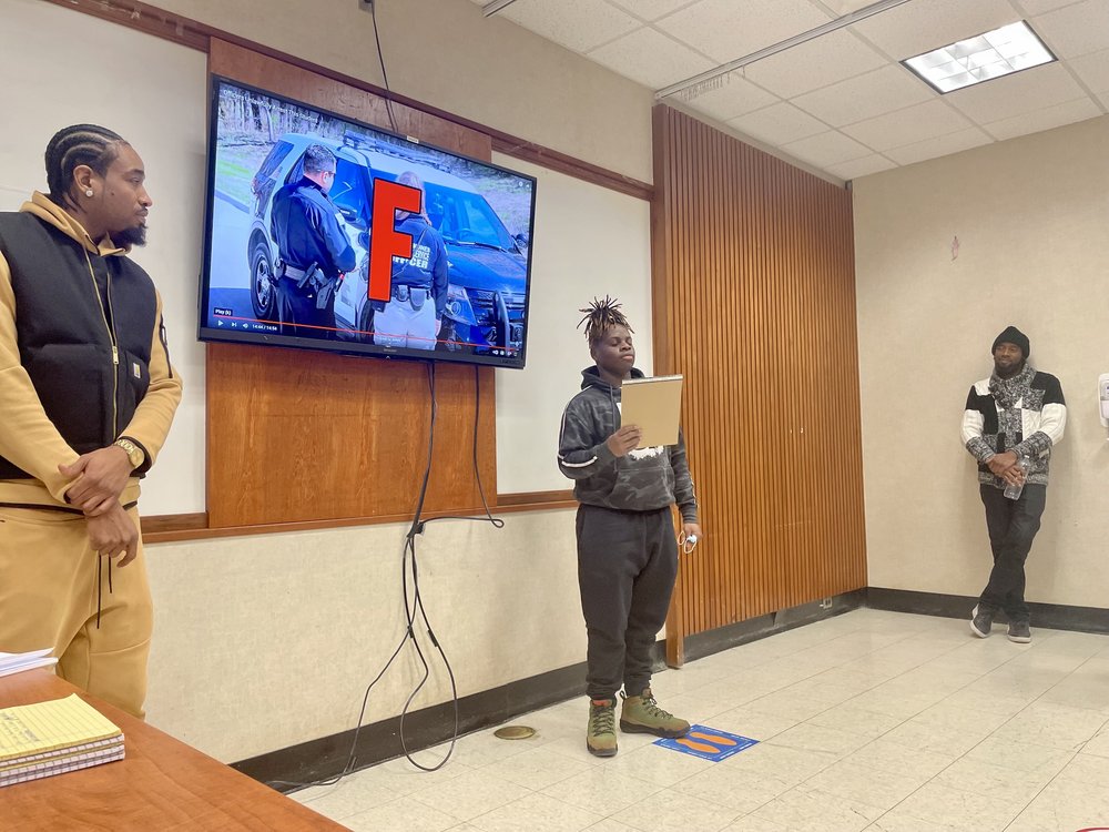 Legal Aid’s Kraig Lewis and Al Saint-Jean listen as Kanye Farrison Stone raps his own lyrics to get practice talking in front of other people.