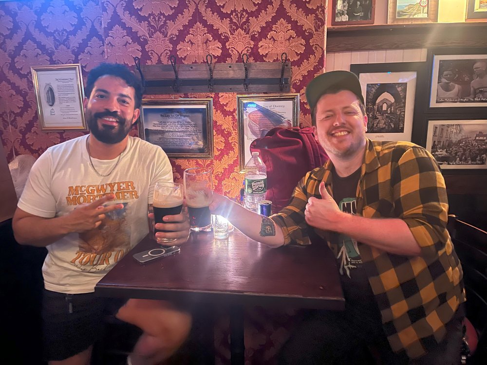 Two men sitting in a bar holding beers.