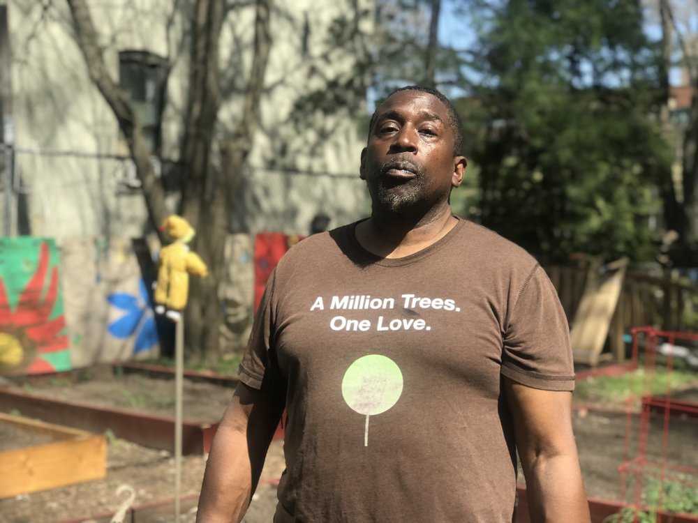 community gardeners Michael Young standing in his garden with a shirt that reads "A million trees. One Love."
