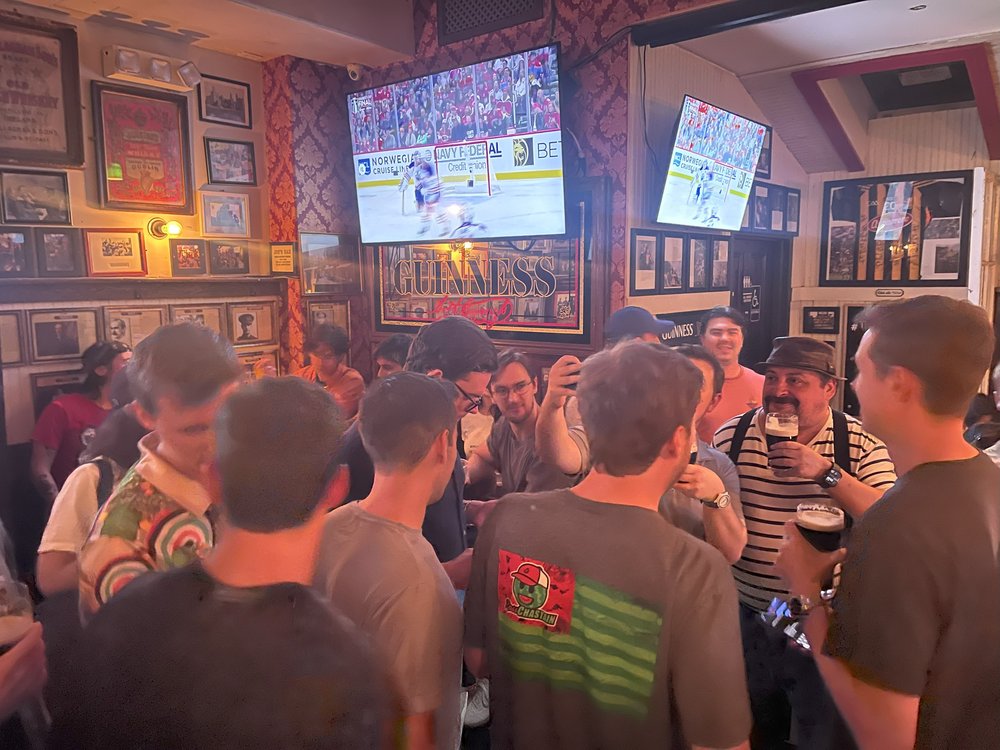 A group of people watch TVs in an Irish pub.