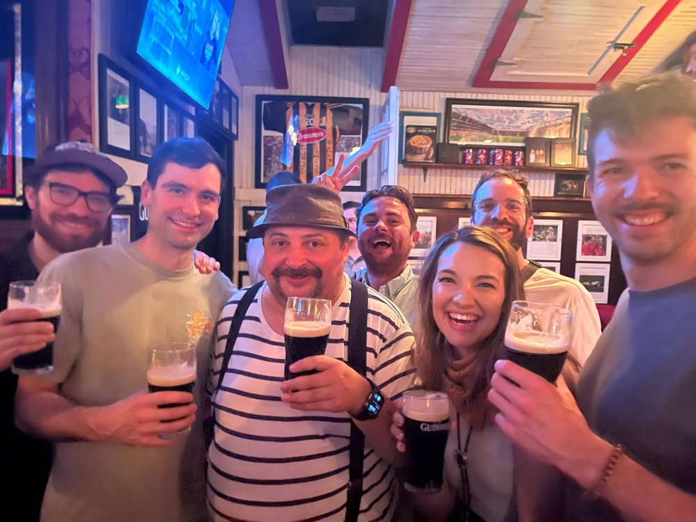 A group of people hold glasses of beer in an Irish pub.