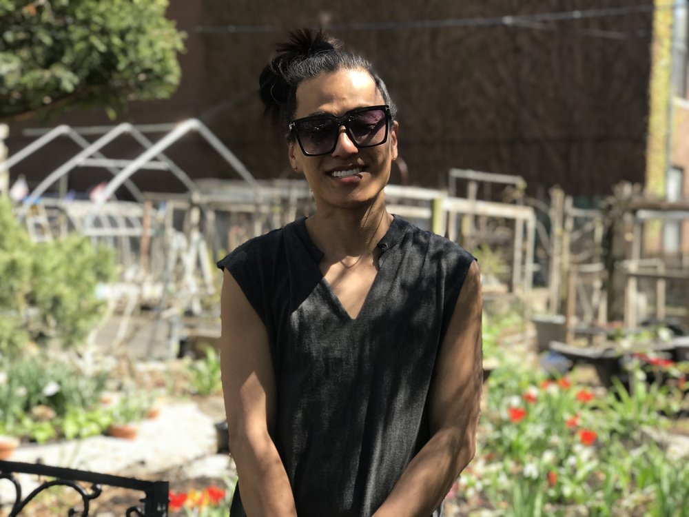 community gardener Kim Yim standing in her garden with flowers and vegetable beds in the background.