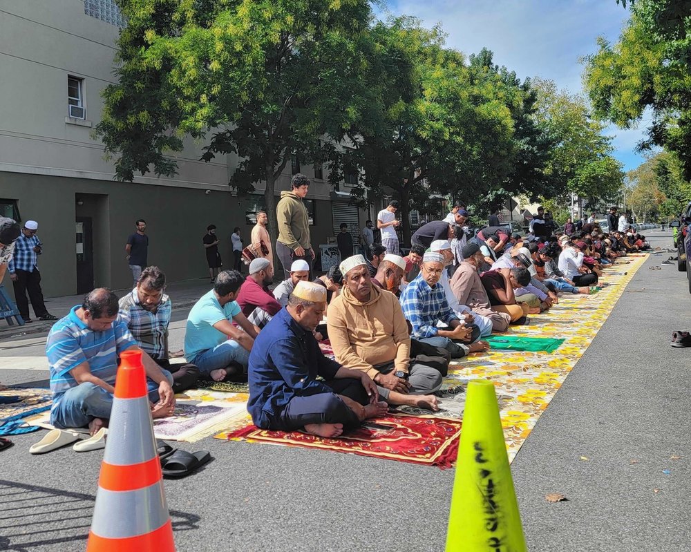 Muslim worshipers sitting on mats in a New York City street.