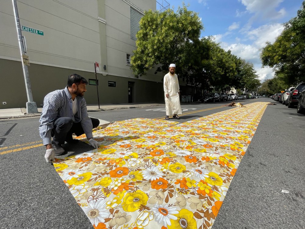 Two Muslim men lay out mats in a Brooklyn street.