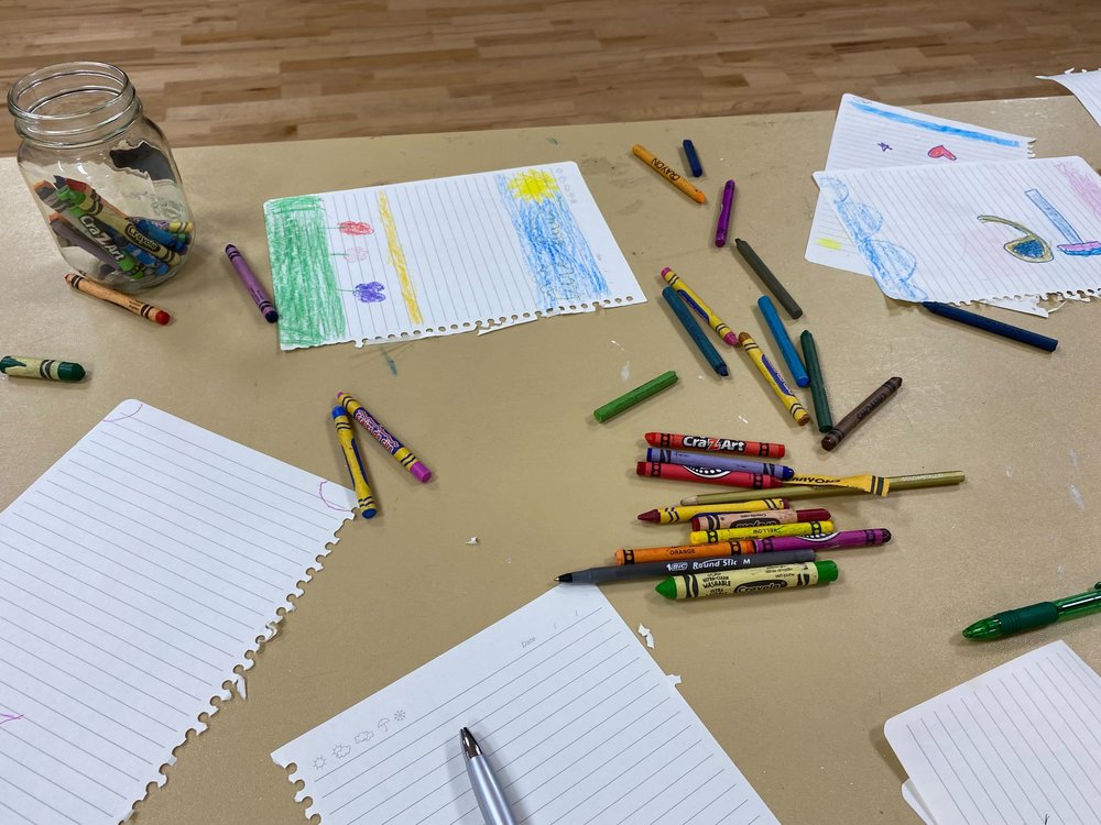 Crayons are splayed out on a table of drawings children made at the Salvation Army Times Square offices.