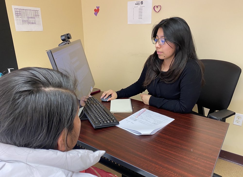 Daniela Juarez Teoyotl, benefits specialist with the Center for Family Life in Sunset Park, jots down a client's information to help her sign up for an IDNYC appointment once slots open later on Friday. March 8, 2024.
