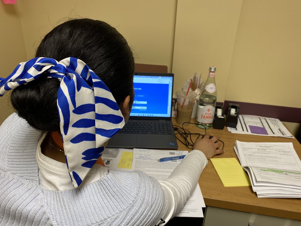A woman wearing a white and blue hair bow toggles through the city's municipal ID website.