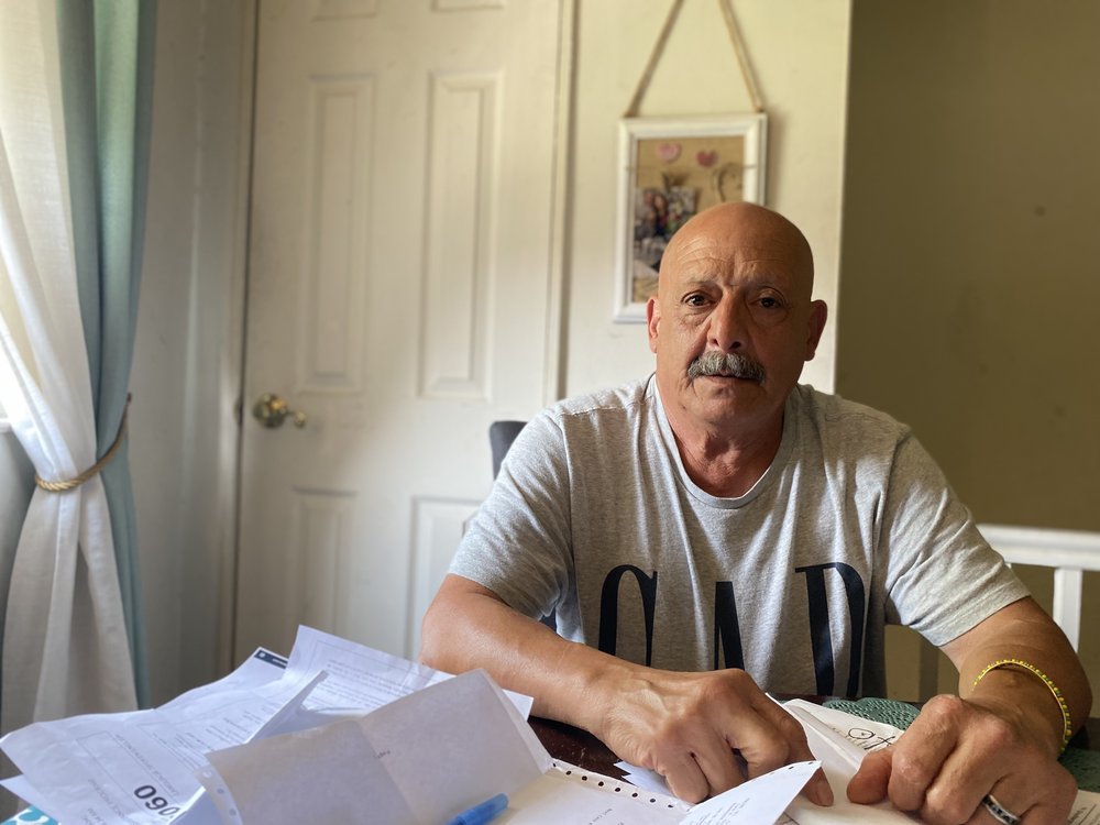Arnaldo Fernandez sits at a table in his apartment that's littered with paperwork.