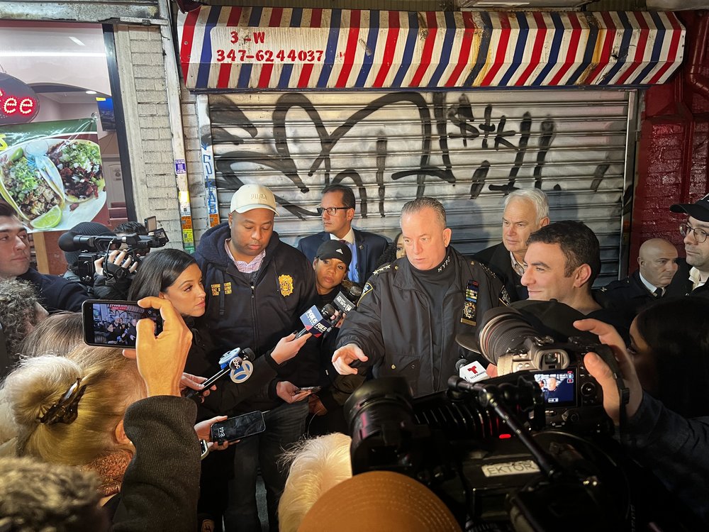 NYPD officials surrounded by reporters.