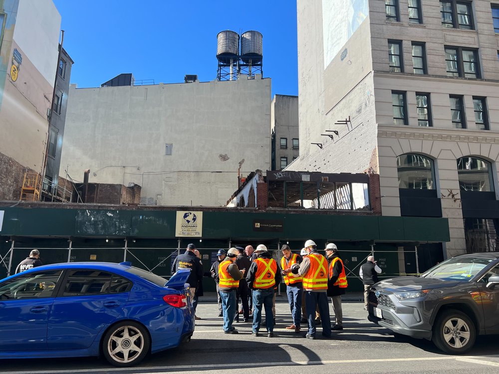 Workers stand outside the building after a wall collapsed on Tuesday.