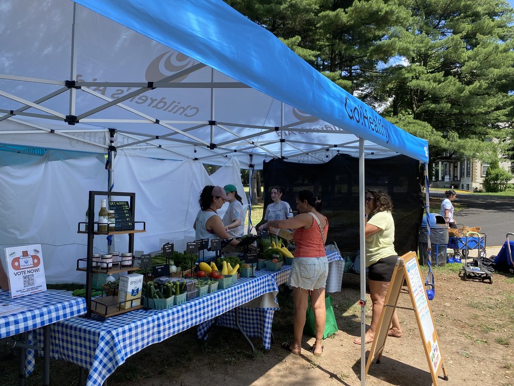 People collect fresh produce at a table.