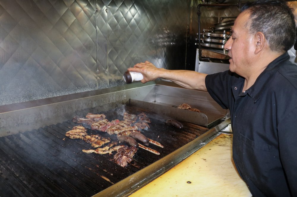 A man grills meat over the fire.