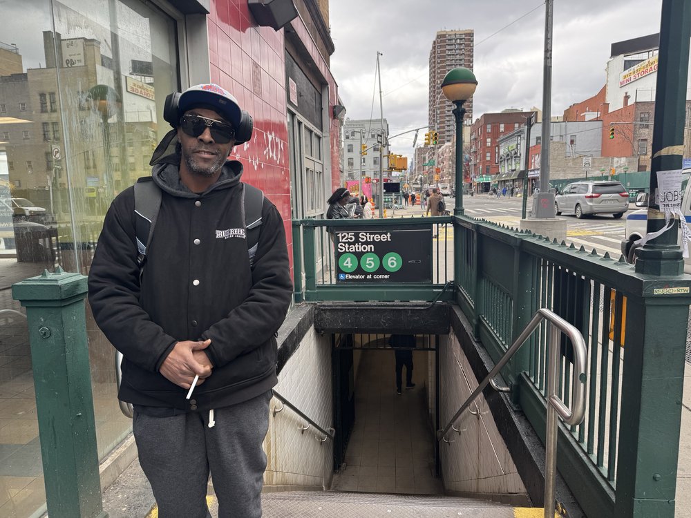 East Harlem resident Bobby Jones stands above his subway stop with an unlit cigarette in hand.