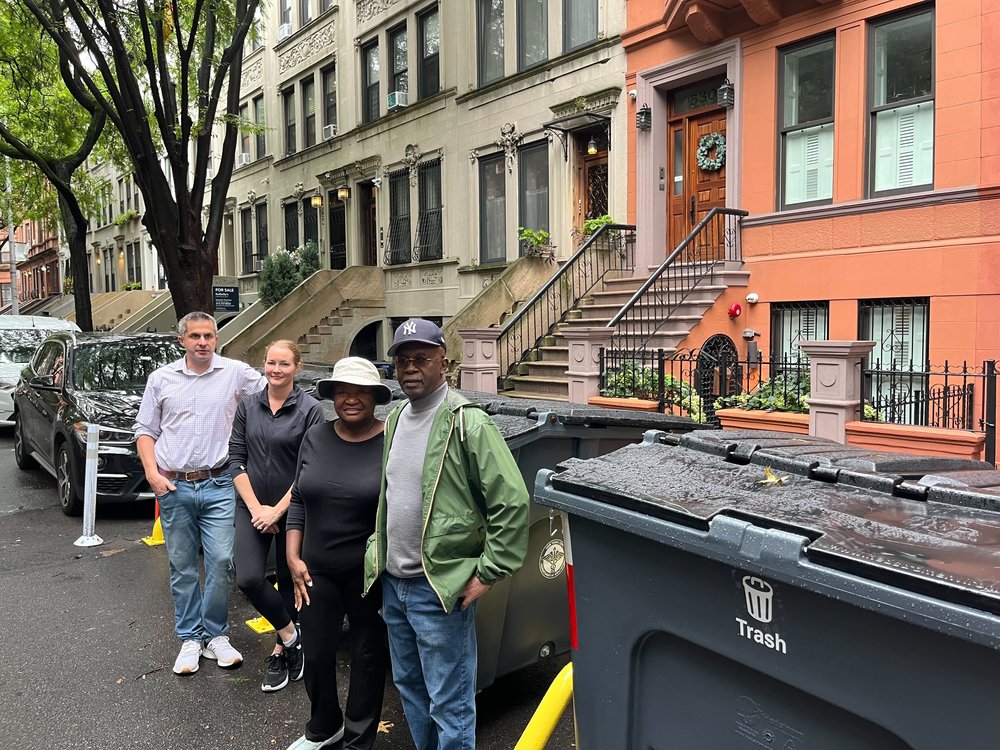 West Harlem residents in front of new trash bins on West 149th Street.