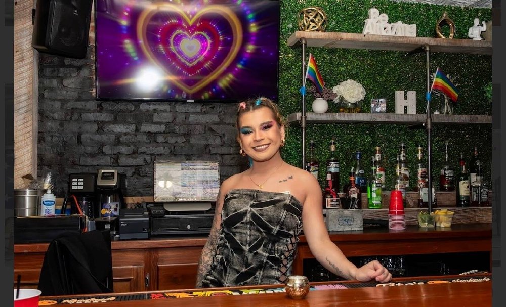 A woman stands behind a bar.