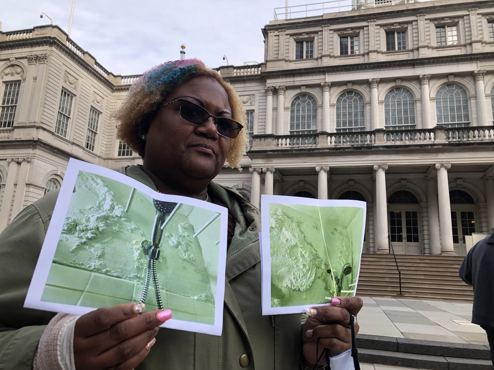 Saundrea I. Coleman holds up two pictures of her moldy bathroom taken a year apart. NYCHA still hasn't come to fix the ongoing issue.