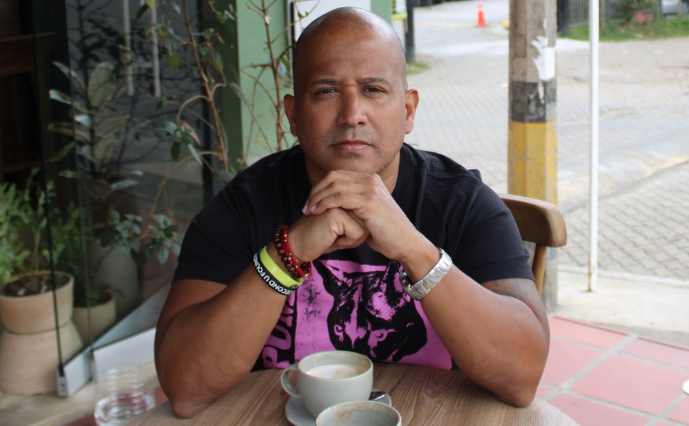 A man seated at a table with a coffee mug.