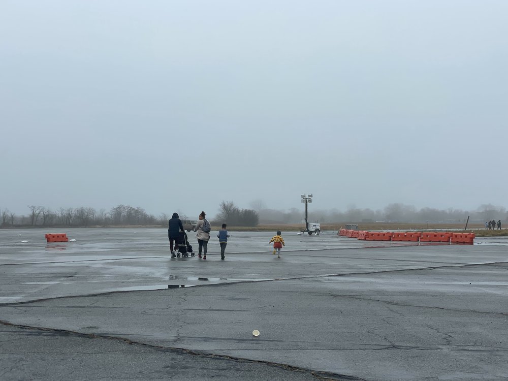 A family of migrants is seen walking near the tent facility at Floyd Bennett Field in Southeast Brooklyn on Dec. 18, 2023.