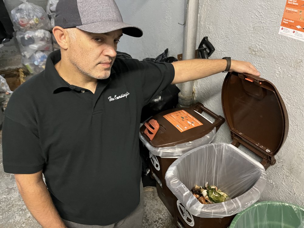 A building worker opens a trash can.