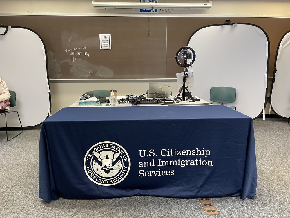 A table set up by U.S. Citizen and Immigration Services at the new intake center for migrant work permit applications at John Jay College in Manhattan on Dec. 1, 2023