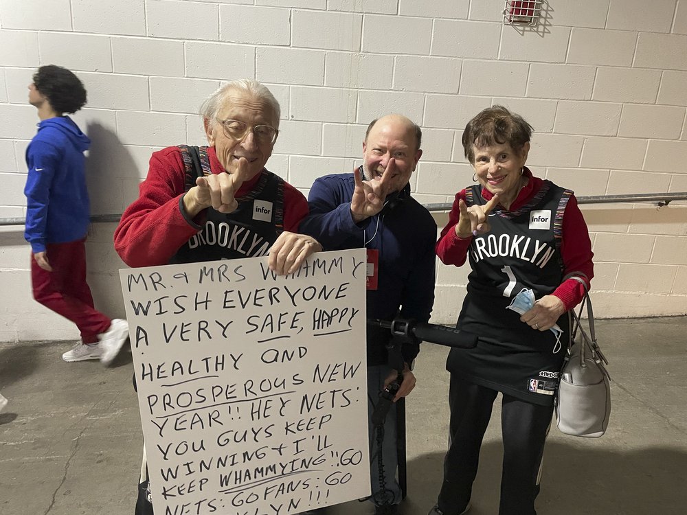 Three people standing together in the corridor outside a basketball arena.