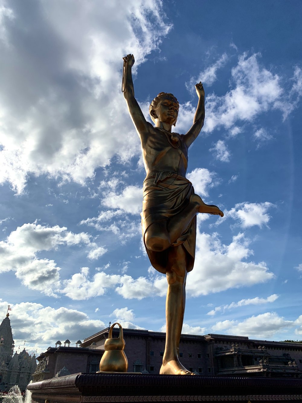 An enormous gilded statue of a young person on one-footed, cross-legged yoga pose.