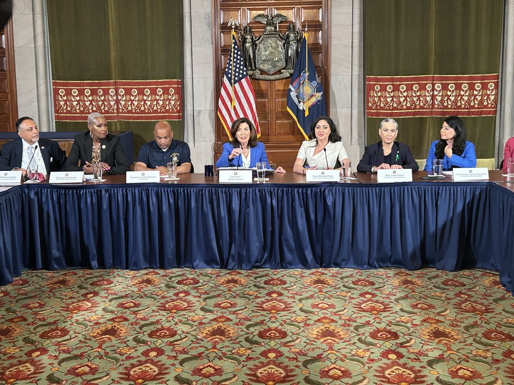 Gov. Hochul flanked by elected officials at a large table.